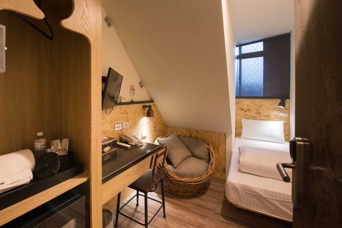 A compact room with a desk, chair, and a bed.