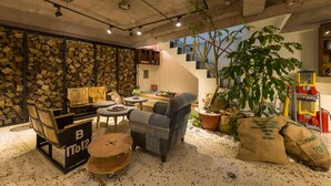 A cozy indoor space with rustic wooden walls, a staircase, and a variety of seating arrangements including a sofa, chairs, and a small table.