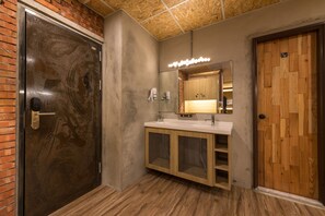 A bathroom with a wooden door, a sink with a mirror, and a shower area. - Beimen Wow Poshtel - Hostel (Taipei)