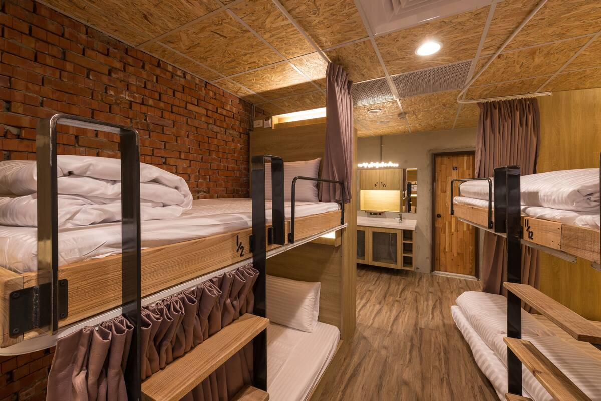 A bunk bed room with a brick wall, wooden ceiling, and a mirror.