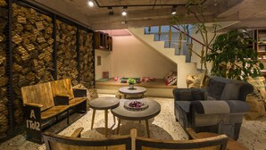 A cozy living area with a wooden bench, a small round table, and a couch. There is a staircase leading to an upper level.