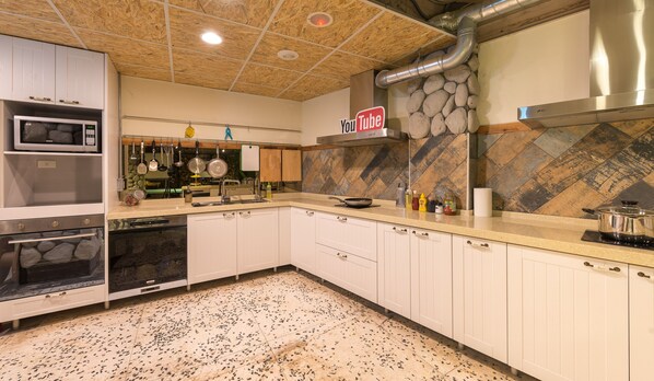 A modern kitchen with white cabinets, stainless steel appliances, a YouTube sign, and a herringbone-patterned backsplash. - Beimen Wow Poshtel - Hostel (Taipei)