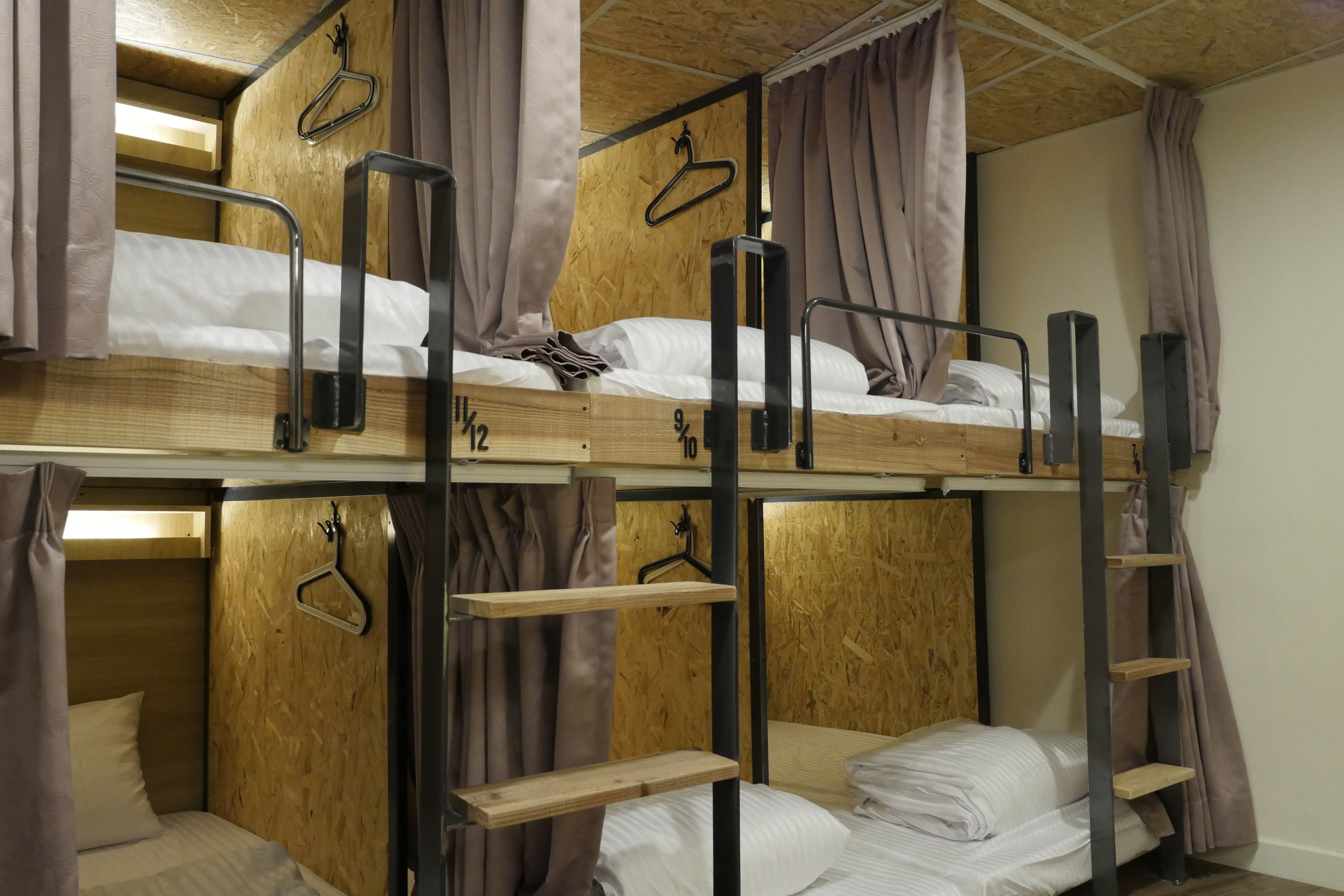 A bunk bed room with wooden walls, metal railings, and hanging curtains.