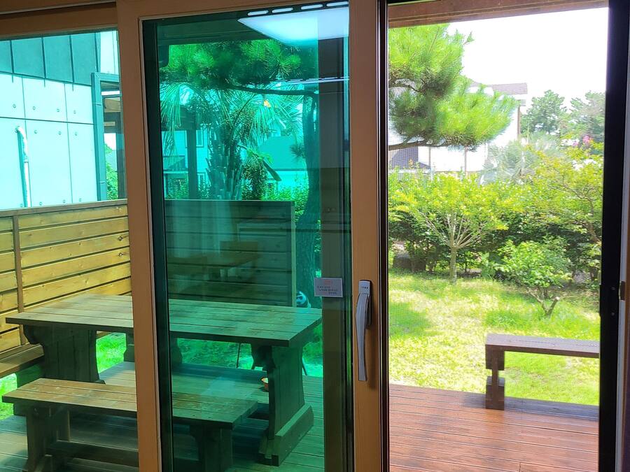 A sliding glass door leading to an outdoor patio area with wooden benches and a table.