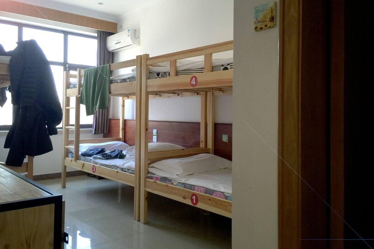 Un dormitorio con literas, numeradas del 1 al 4, y una ventana con cortinas.