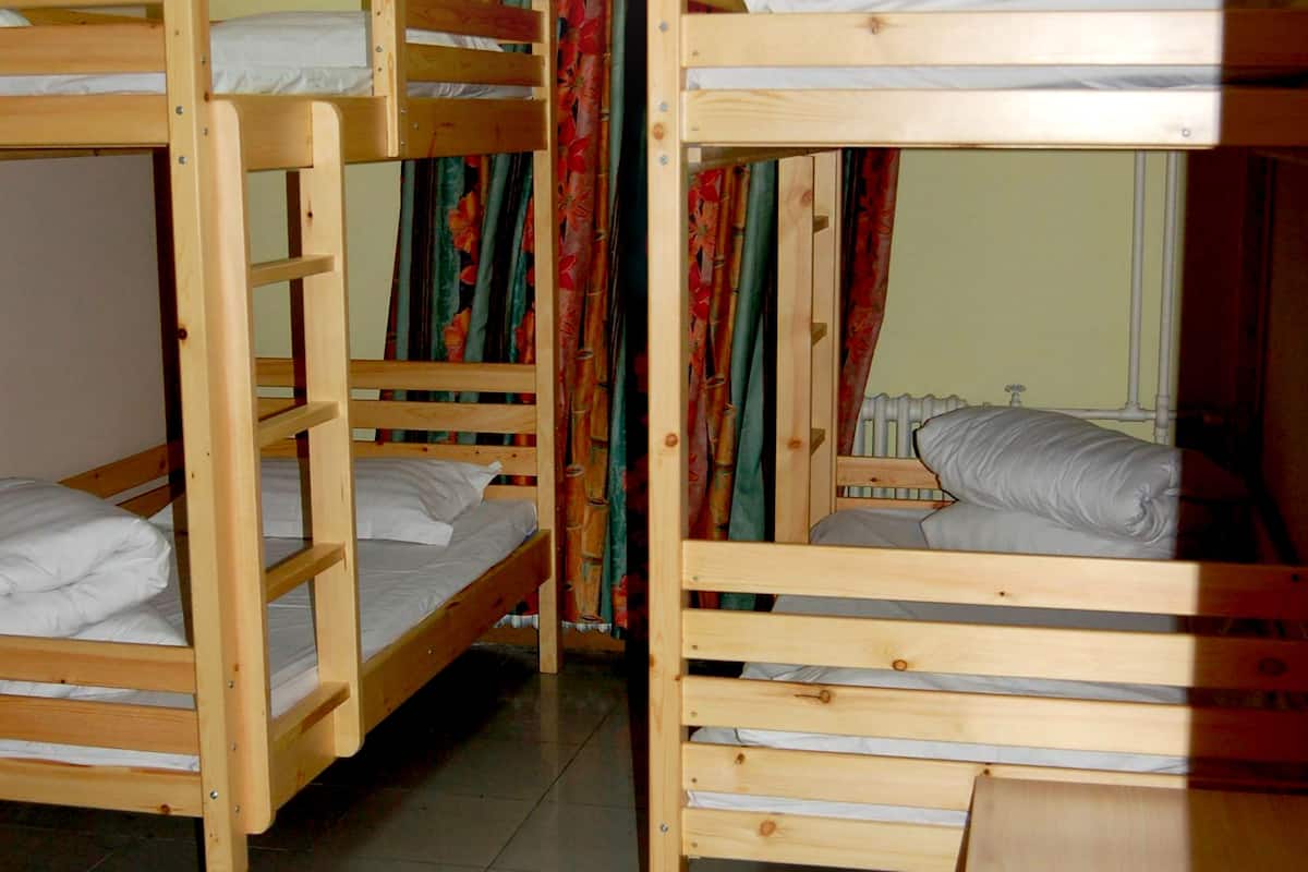 Un dormitorio con literas, una cortina y un radiador.