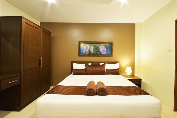 Una habitación de hotel con una cama grande, un armario, un cuadro en la pared y una lámpara de noche.
