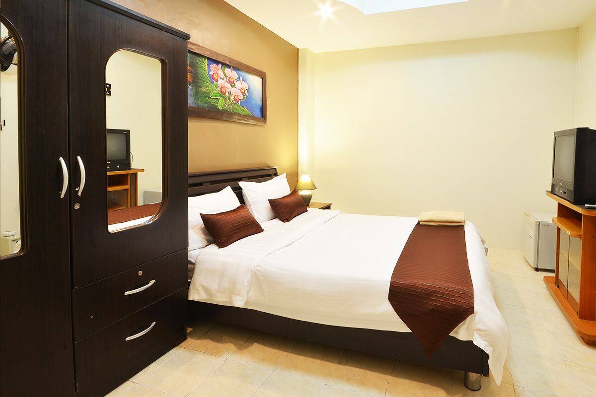 Een hotelkamer met een bed, een kledingkast, een televisie en een schilderij aan de muur.
