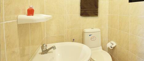 A bathroom with a white sink, toilet, and beige tiled walls.
