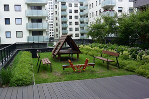 Relax in a serene garden setting with a playhouse, bench, and wooden seesaw.