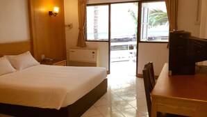 Une chambre d’hôtel avec un lit, un bureau, une télévision et une fenêtre avec des rideaux.
