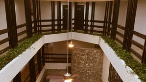 Un atrium à plusieurs niveaux, doté d’un espace central aménagé en salon, de murs en pierre et de rampes en bois.