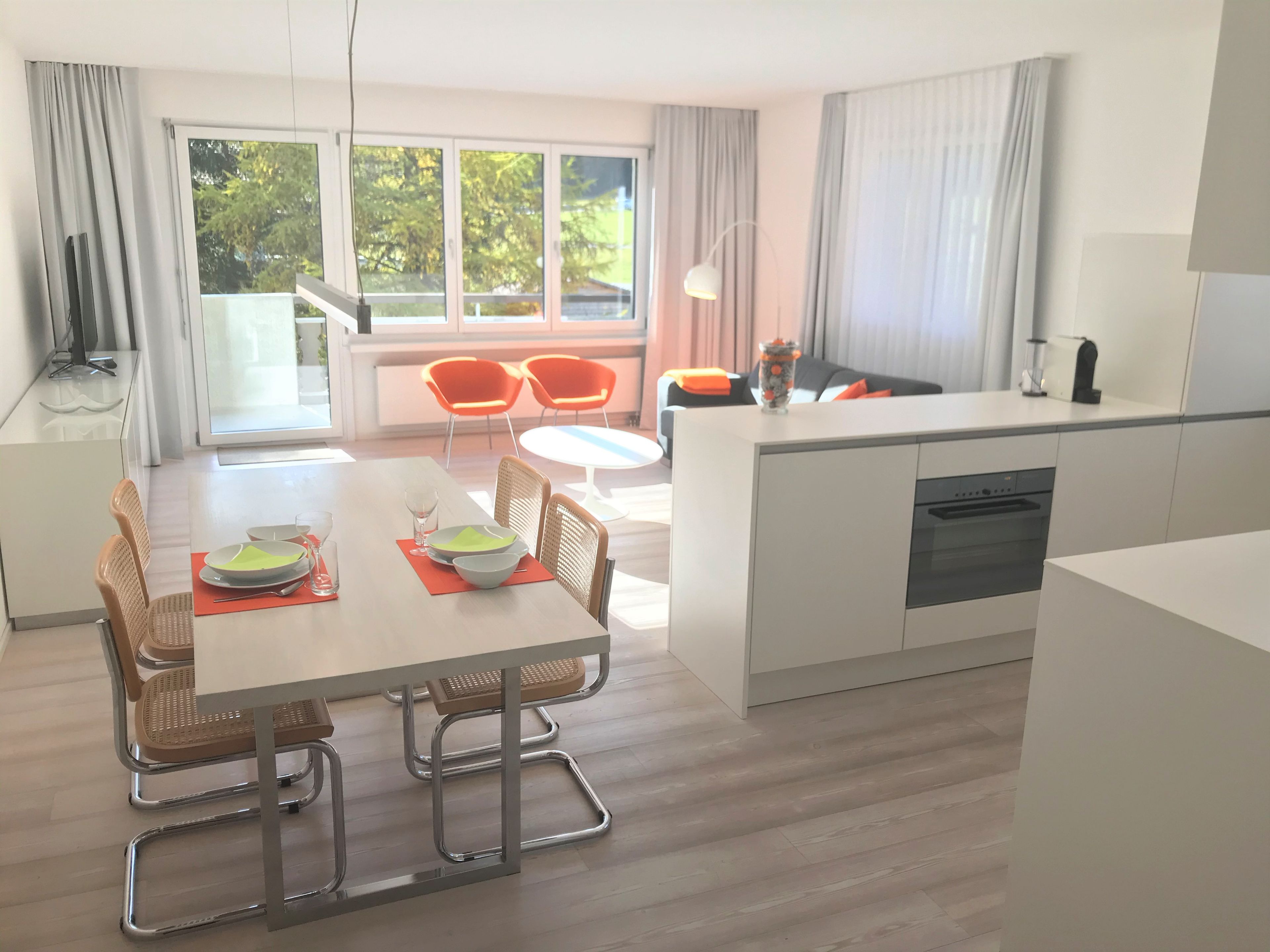 Una cocina moderna con comedor, ventanas amplias y vistas al verdor.
