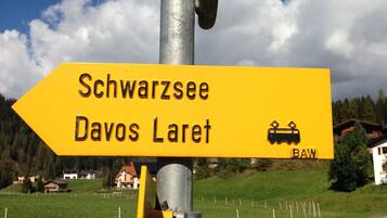 Un cartel direccional con la inscripción 'Schwarzsee Davos Laret' y un símbolo de tren, montado sobre un poste metálico.