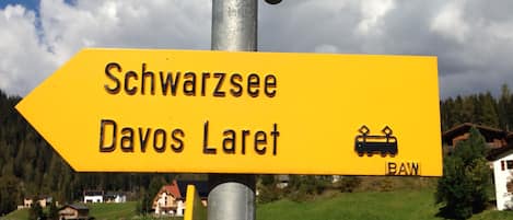 Un cartel direccional con la inscripción 'Schwarzsee Davos Laret' y un símbolo de tren, montado sobre un poste metálico.