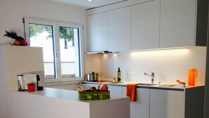 Een moderne keuken met witte kasten, een centraal eiland en een raam voor natuurlijk licht.