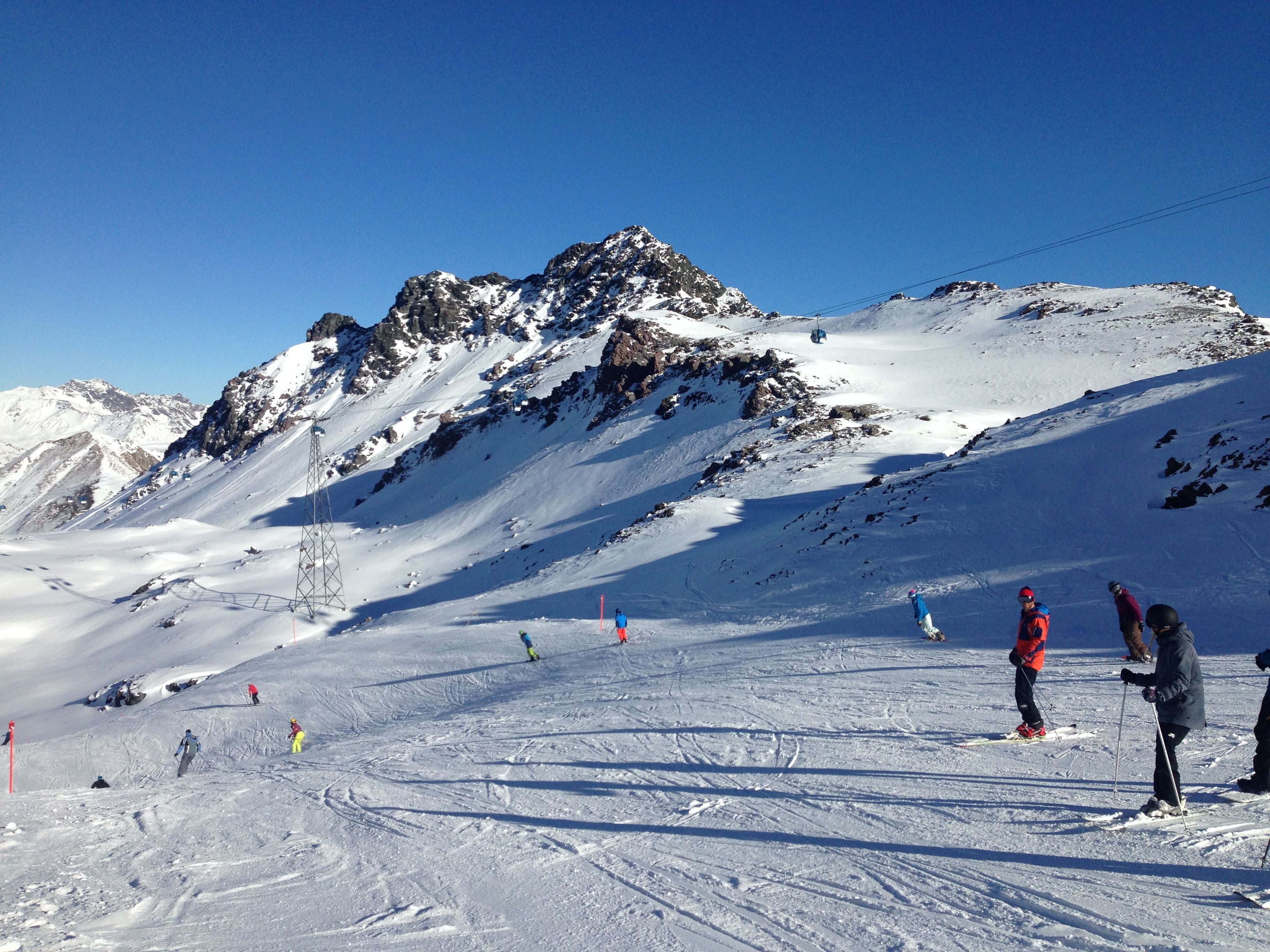 A snowy mountain slope with skiers and a ski lift.