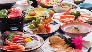 Une variété de plats de fruits de mer, notamment des crevettes, des queues de crabe et du sashimi, présentés sur une table avec de nombreux bols et assiettes.