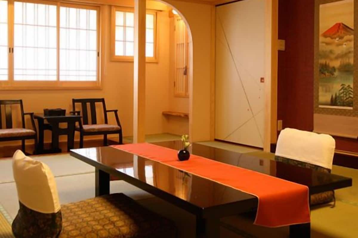 Una habitación tradicional japonesa con esteras de tatami, una mesa baja y un puertas correderas.