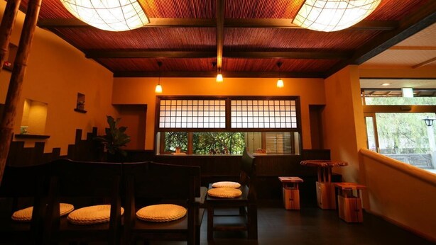 Une pièce de style japonais traditionnel, avec un sol recouvert de tatamis, de petites tables basses en bois et une vue à travers un paravent shoji.
