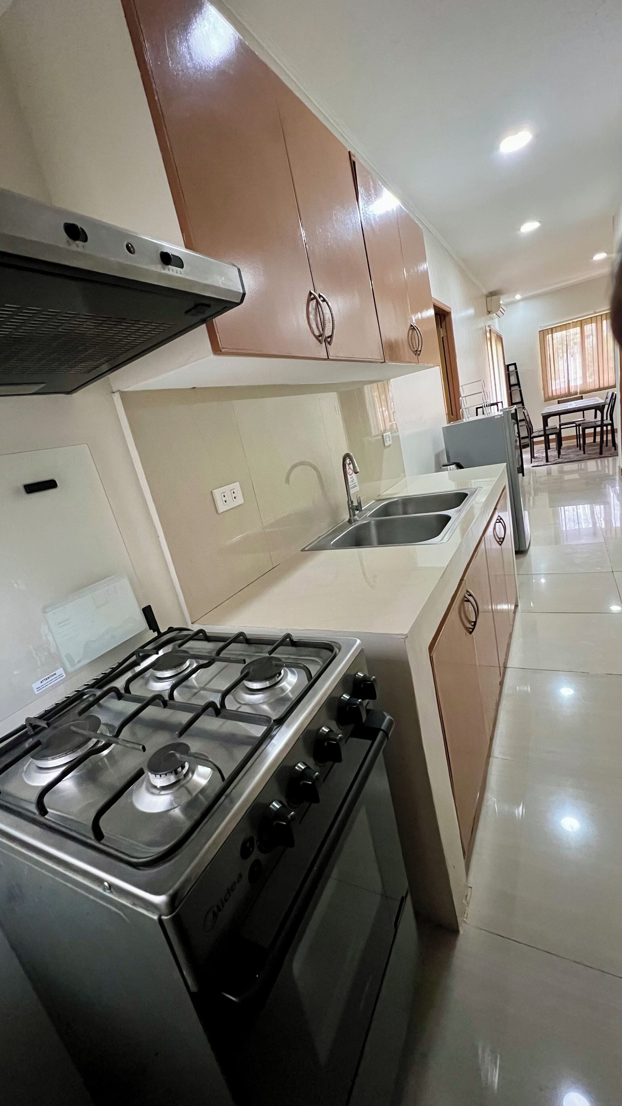 A kitchen with a gas stove, a sink, and wooden cabinets.