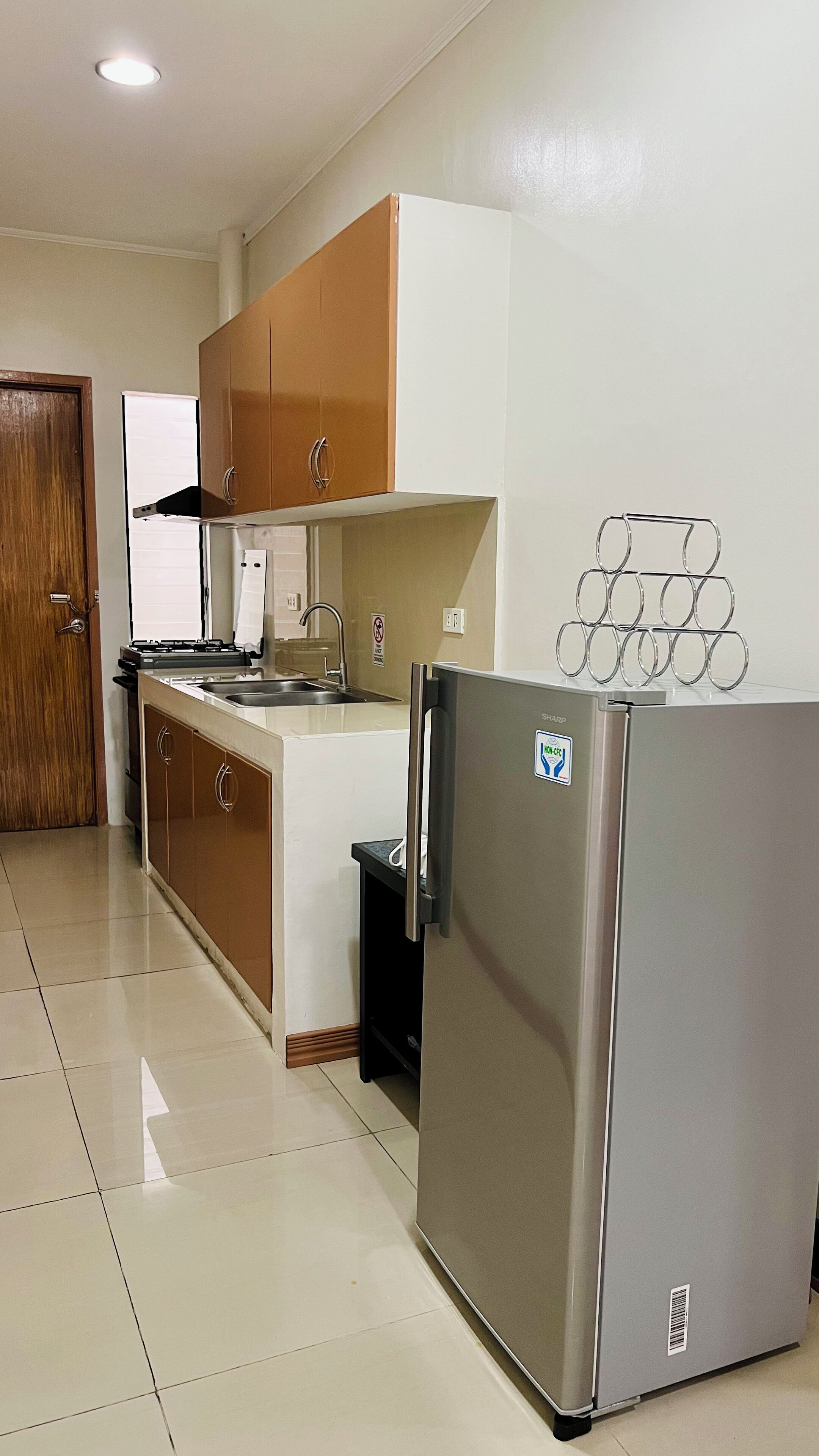 A kitchen with a refrigerator, stove, sink, and wooden cabinets.