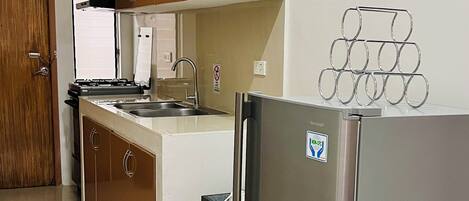 A kitchen with a refrigerator, stove, sink, and wooden cabinets.