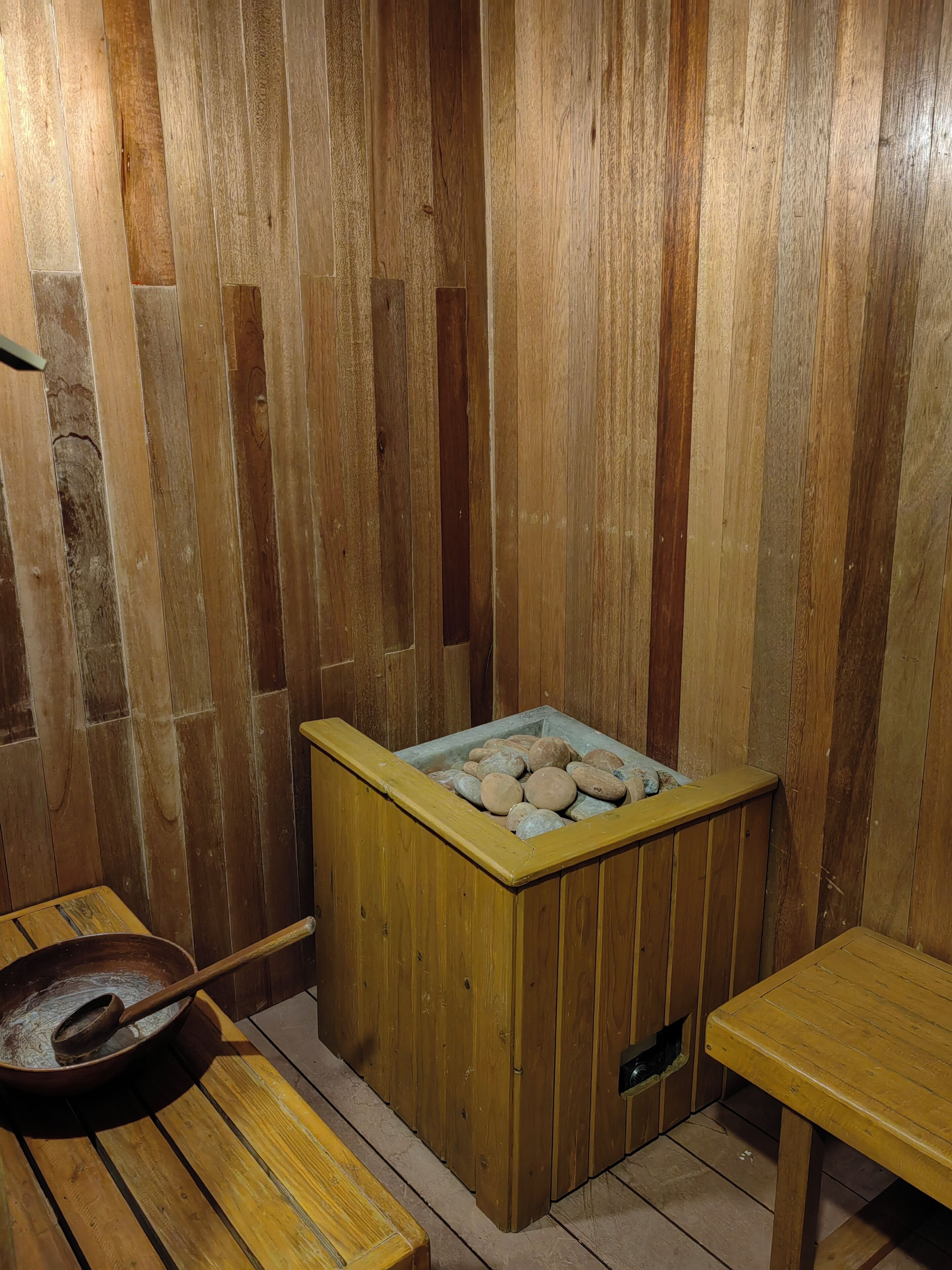 A wooden sauna with benches and a stone-filled basin.