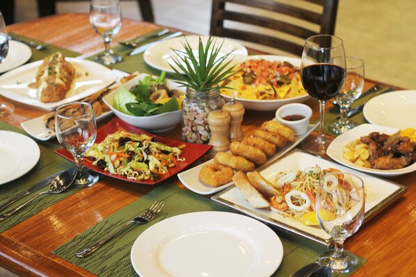 A dining table set with various dishes, including salads, fried items, and seafood, along with wine glasses and cutlery. - Batangas Country Club (Batangas City)