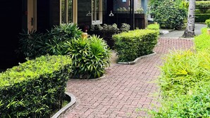 A building with a dark facade and a green roof, surrounded by lush greenery and palm trees. - Batangas Country Club (Batangas City)