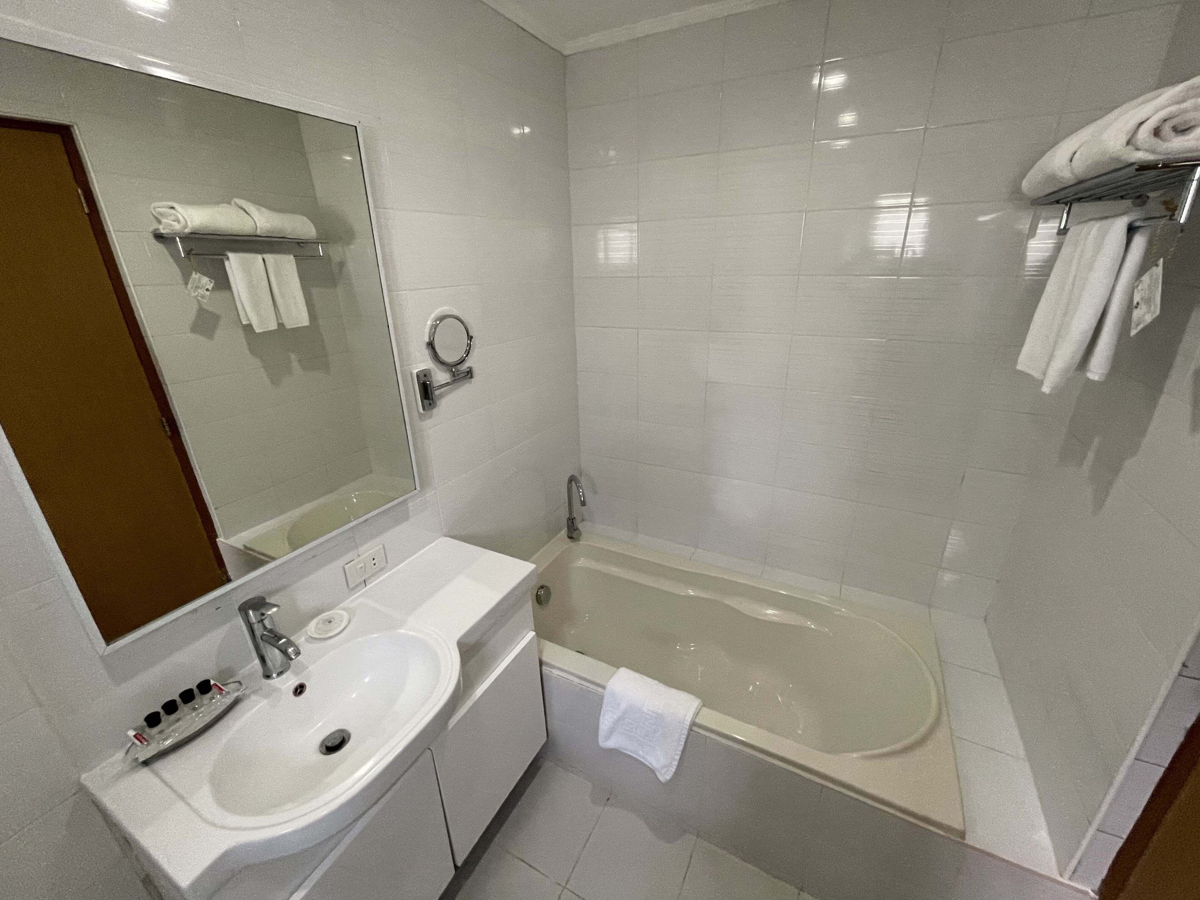 A bathroom with a sink, mirror, and bathtub.