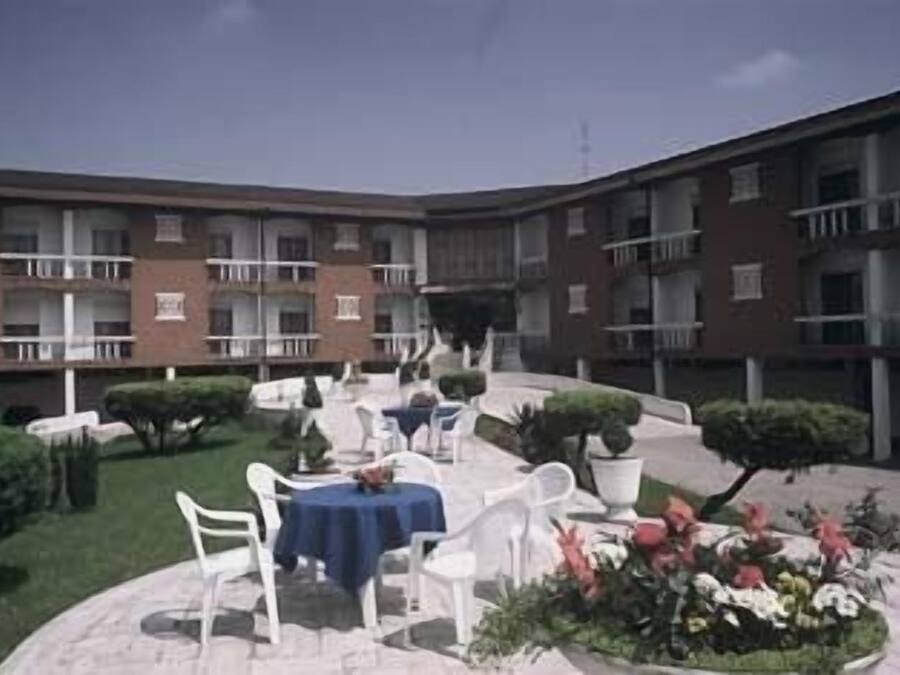 A courtyard with outdoor seating, a small garden, and a multi-story building with balconies.