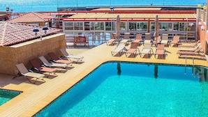 A pool area with sun loungers and a view of the sea. - Hotel Vulcão (Cidade Velha)