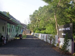 A gravel driveway leading to a building with a sign reading "LANTA TRIPLE NOVEL Welcome".