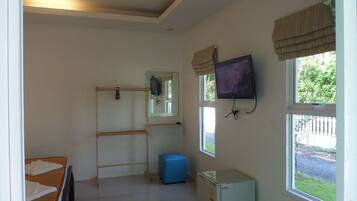 Una habitación con cama, un escritorio pequeño, televisión, ventana y radiador.