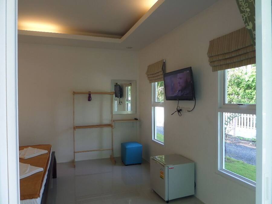 Una habitación con cama, un escritorio pequeño, televisión, ventana y radiador.