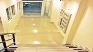 A staircase leading to a landing with a glass door and a poster on the wall. - Santa Place (Pattaya)