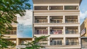 A multi-story building with balconies, a ground-level entrance, and a visible storefront with clothing items. - Santa Place (Pattaya)