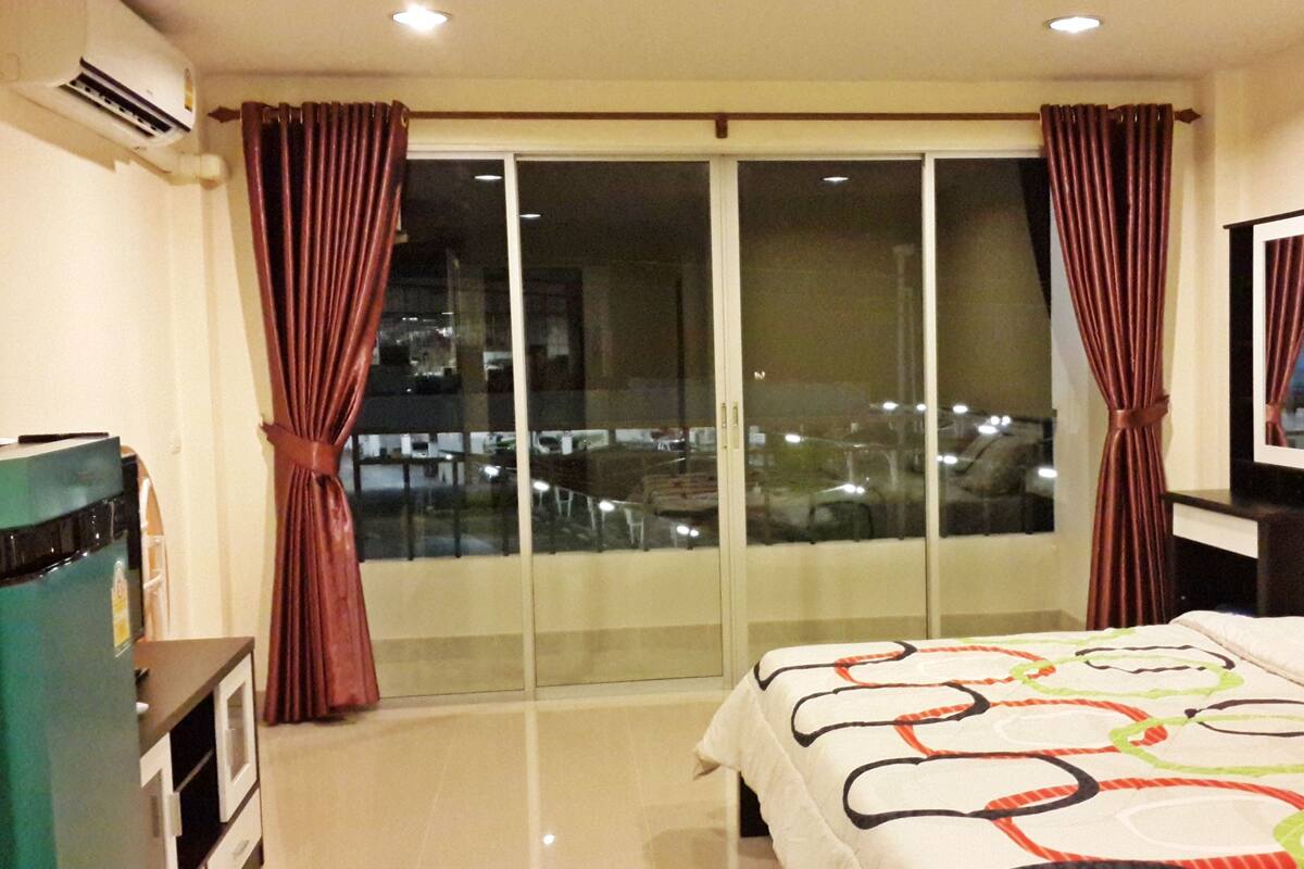A hotel room with a bed, a TV, a desk, and a sliding glass door to the balcony.
