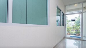 A hallway with a large window and a door leading outside. - Santa Place (Pattaya)