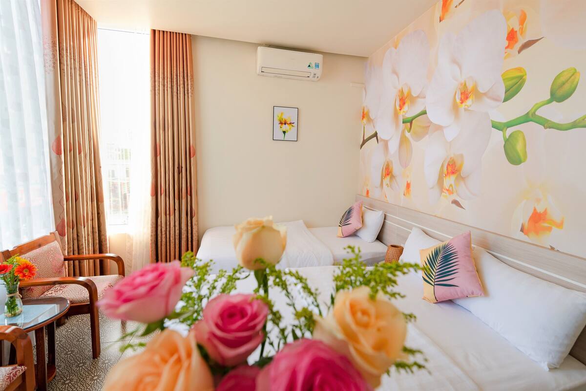 Una habitación de hotel con una cama, dos mesitas de noche, una silla y una ventana con cortinas.