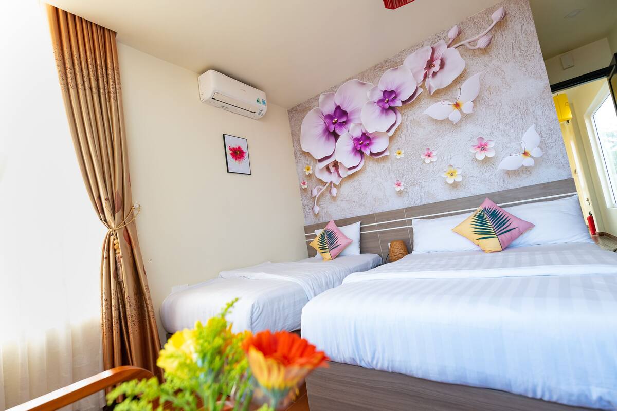 Habitación de hotel con dos camas, aire acondicionado de pared y decoración floral.