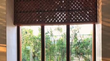 Ein Essbereich mit Korbstühlen und einem Tisch für sechs Personen, mit Blick auf einen Garten durch große Fenster.