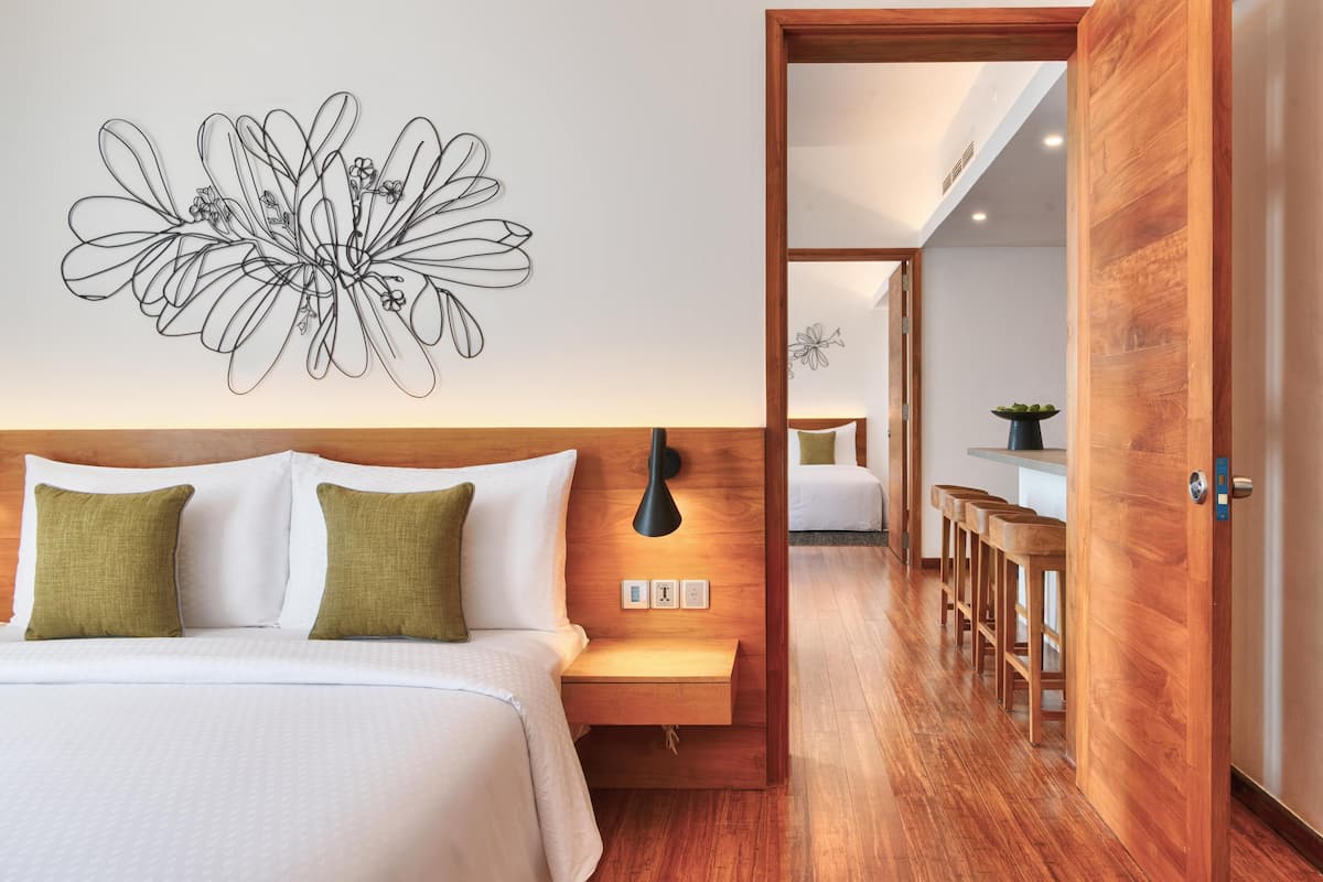 Une chambre d’hôtel comprenant un lit, une table de chevet, une lampe et une œuvre d’art murale.