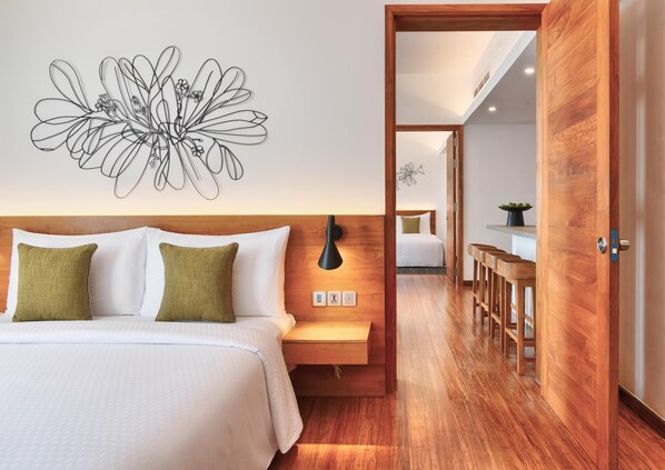 A hotel room with a bed, bedside table, lamp, and a wall art piece. - Jetwing Colombo Seven (Colombo)
