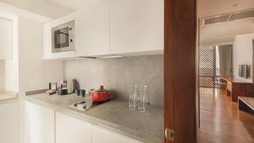 Una cocina moderna con microondas, cafetera y una olla roja sobre la encimera.