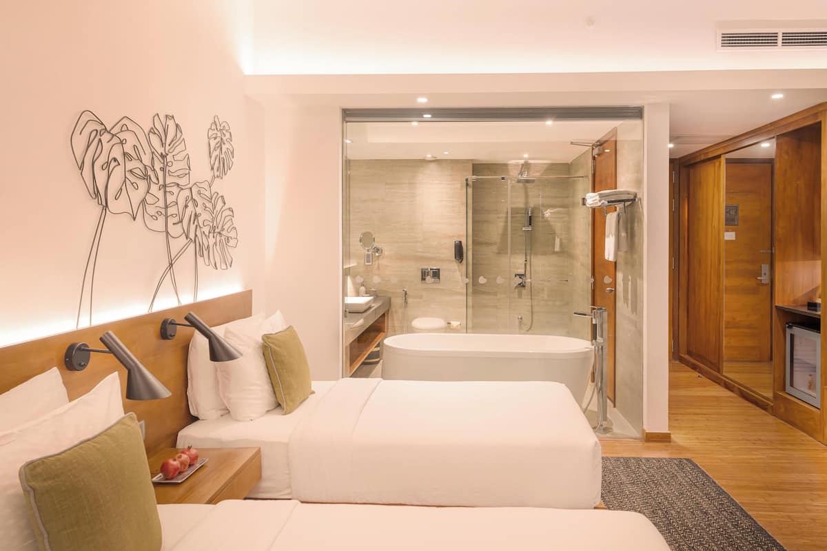 Une chambre d’hôtel moderne dotée d’un grand lit, d’une douche séparée à parois de verre, d’une salle de bain indépendante et d’une armoire en bois.