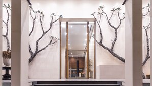 A modern interior with a staircase leading to a reception area, featuring a minimalist design with branches and a glass partition. - Jetwing Colombo Seven (Colombo)