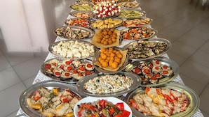 A buffet table with various dishes and a vase of flowers in a room with chairs and tables.