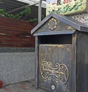 A rustic metal birdhouse with a decorative emblem on the roof and a keyhole on the front. - Yi Homestay (Taitung)